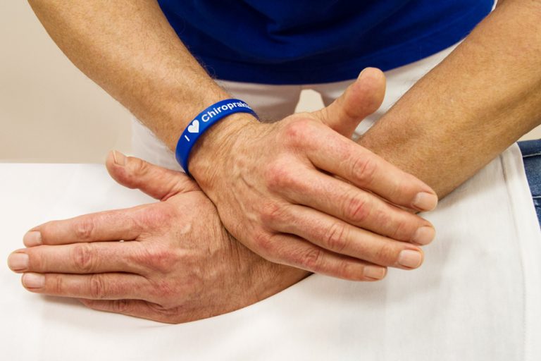 Eine Person liegt Bäuchlings auf einer Liege und bekommt eine Behandlung am Rücken.