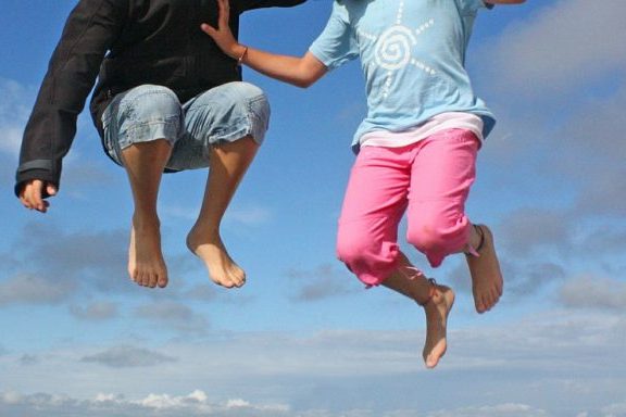 Zwei Kinder springen in die Luft.