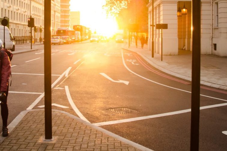 Ein Stadtbild mit einem Fahrradfahrer, vor einem Sonnenuntergang.