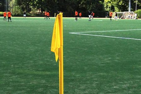 Eckfahne auf einem Fußballfeld, auf dem eine Mannschaft spielt.