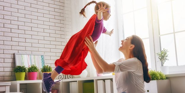 Eine Mama spielt mit ihrem Kind Superwoman.