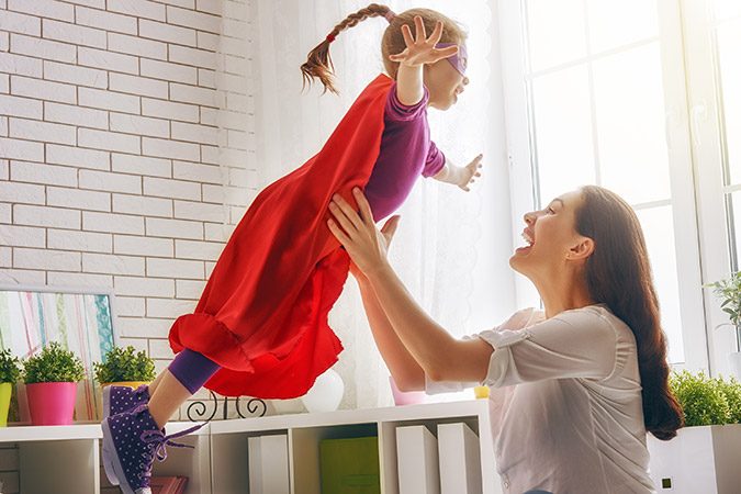 Eine Mama spielt mit ihrem Kind Superwoman.