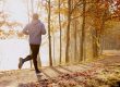 Ein junger Mann joggt entlang eines Flussufers im Wald.