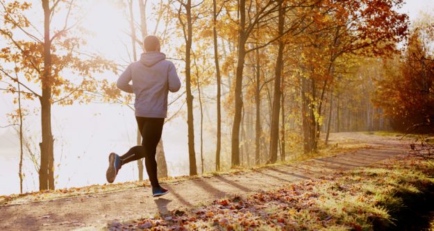 Bewegung, Sport und ganzheitliches Wohlbefinden Ein junger Mann joggt entlang eines Flussufers im Wald.