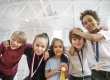 Kinder, die glücklich Medaillen tragen und sich zur Kamera runterbeugen