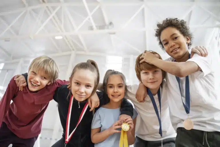 Kinder, die glücklich Medaillen tragen und sich zur Kamera runterbeugen