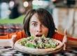 Frau mit einer Pizza in einer Bar