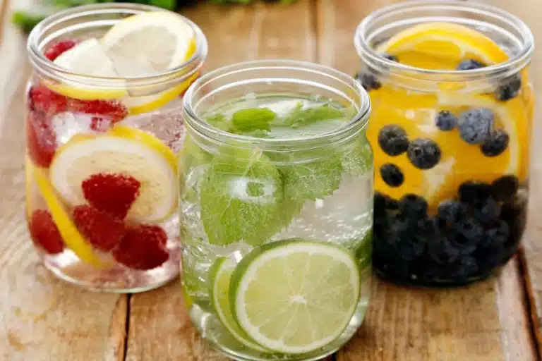 Drei Trinkgläser, die mit Wasser und verschiedenen Früchten gefüllt sind.